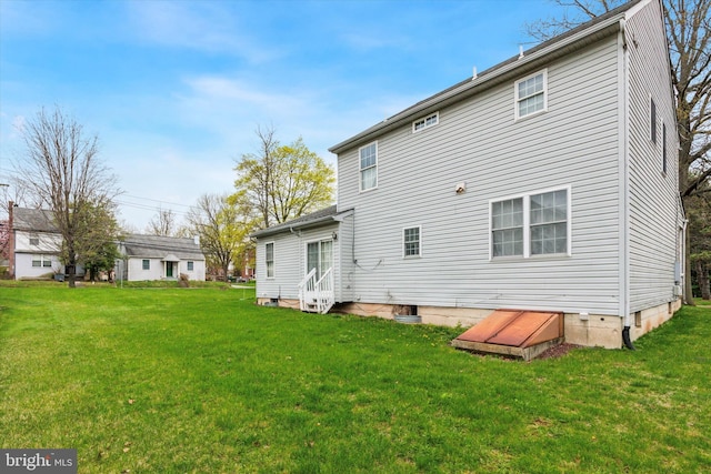 rear view of property featuring entry steps and a lawn