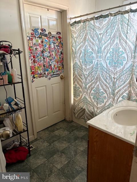 bathroom with curtained shower, vanity, and stone finish flooring