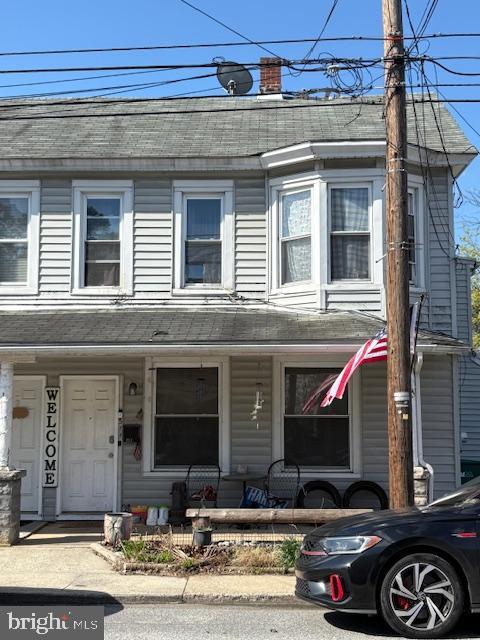 multi unit property featuring roof with shingles and covered porch