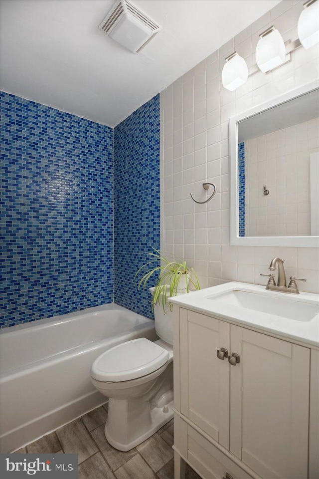 5650 Warren Dr, Huntingtown, MD 20639 - bathroom with visible vents, vanity, wood finished floors, toilet, and tile walls