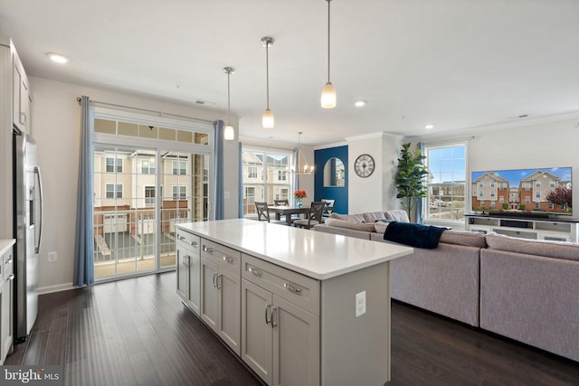 kitchen with dark wood-type flooring, open floor plan, light countertops, and stainless steel fridge