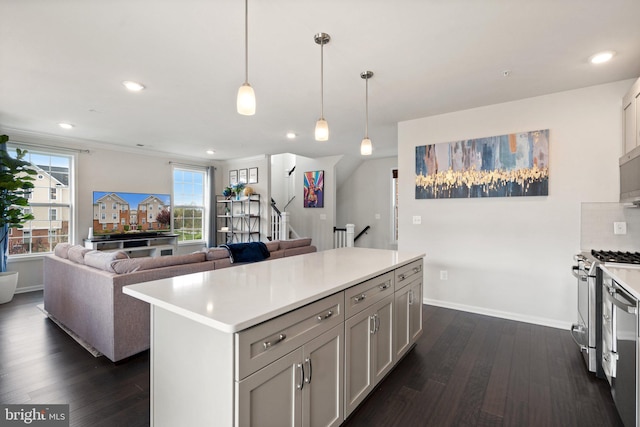 kitchen with baseboards, light countertops, dark wood-type flooring, stainless steel range with gas cooktop, and hanging light fixtures