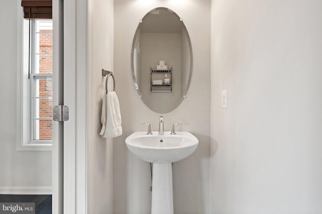 bathroom with baseboards, a sink, and a healthy amount of sunlight