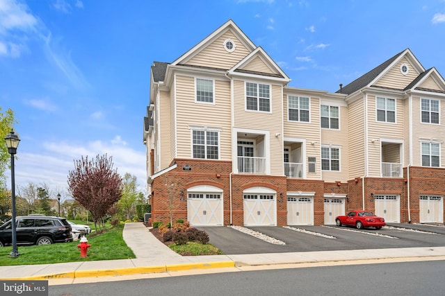 multi unit property featuring brick siding, an attached garage, and driveway