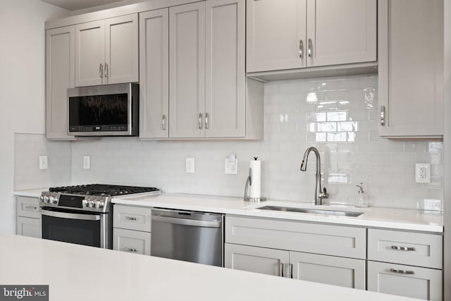 kitchen featuring light countertops, tasteful backsplash, a sink, and stainless steel appliances