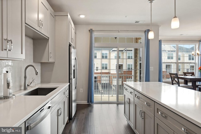 kitchen featuring dark wood-type flooring, appliances with stainless steel finishes, a sink, light countertops, and decorative backsplash
