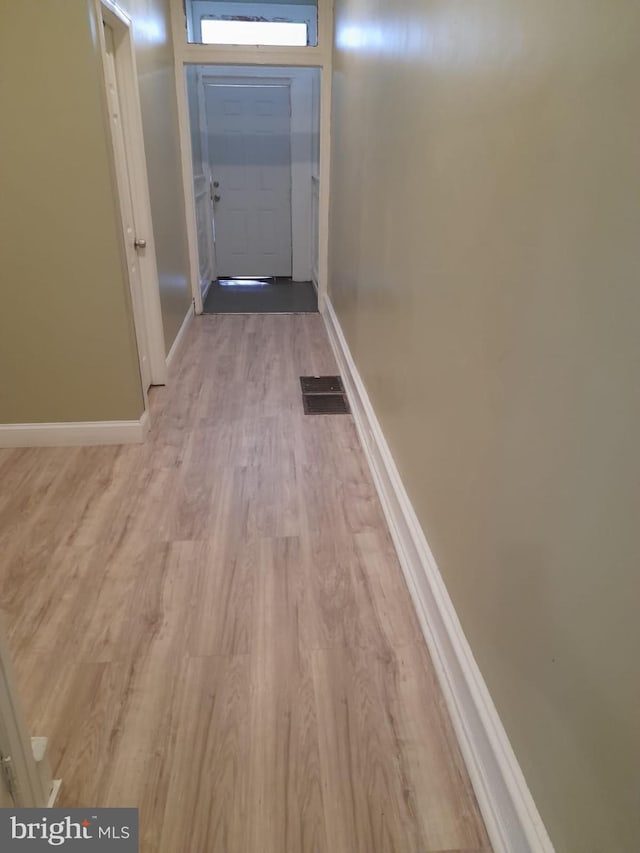 hallway with baseboards, light wood-style flooring, and visible vents