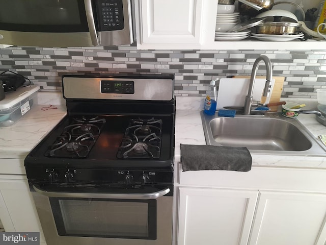 details with white cabinets, stainless steel appliances, decorative backsplash, and a sink