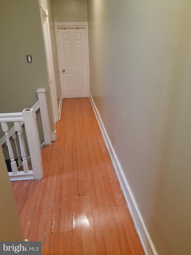 corridor featuring light wood-style flooring and baseboards