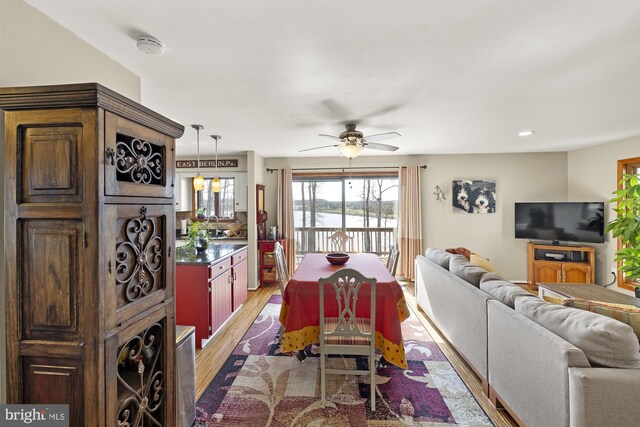 dining room with light wood finished floors, a ceiling fan, and recessed lighting