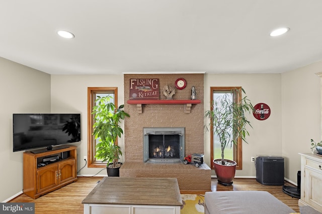 living room featuring baseboards, recessed lighting, light wood-style floors, and a fireplace