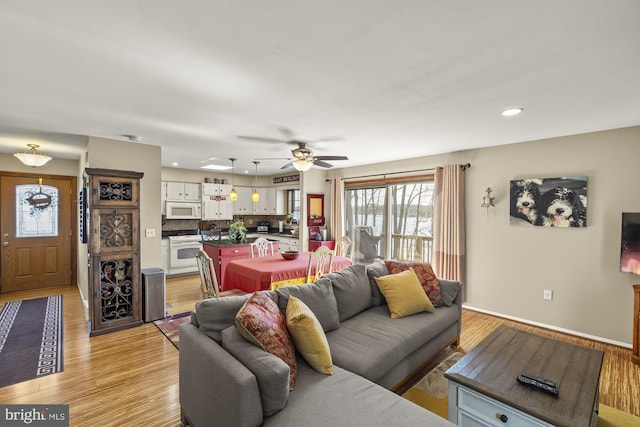 living area featuring light wood-type flooring, a ceiling fan, recessed lighting, and baseboards