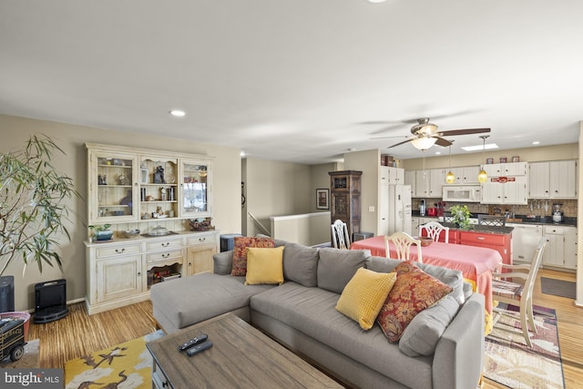living area featuring light wood-style floors, a ceiling fan, and recessed lighting
