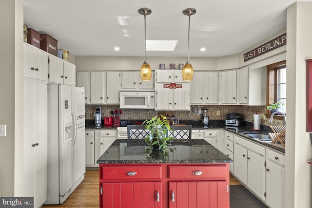kitchen with backsplash, a sink, white appliances, and a kitchen island