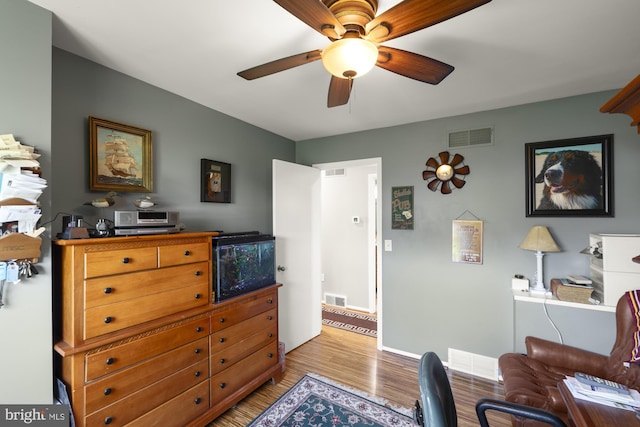 home office featuring light wood finished floors, ceiling fan, and visible vents
