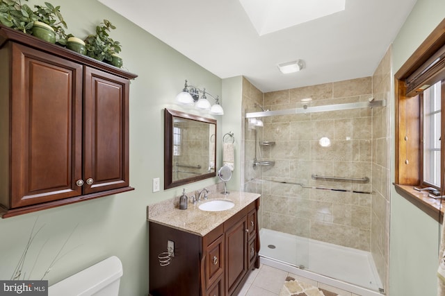 bathroom with tile patterned flooring, vanity, a tile shower, and toilet