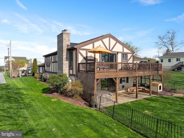 rear view of house with a patio area, a yard, a chimney, fence, and a wooden deck