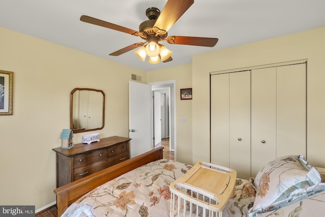 bedroom featuring visible vents, a closet, baseboards, ceiling fan, and wood finished floors