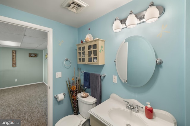 bathroom featuring vanity, baseboards, a paneled ceiling, toilet, and visible vents