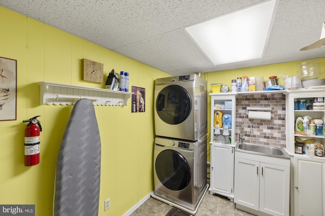 clothes washing area featuring a sink, cabinet space, and stacked washer / drying machine