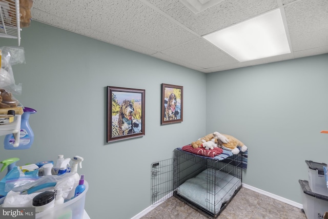 interior space featuring a paneled ceiling and baseboards