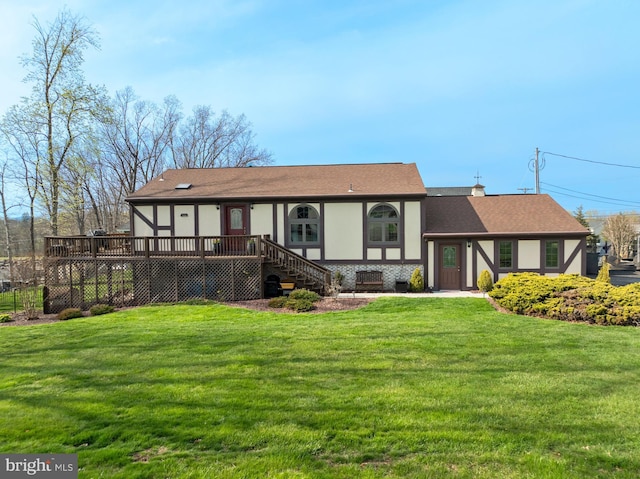 view of front of house featuring roof with shingles, a wooden deck, a front yard, and stairway