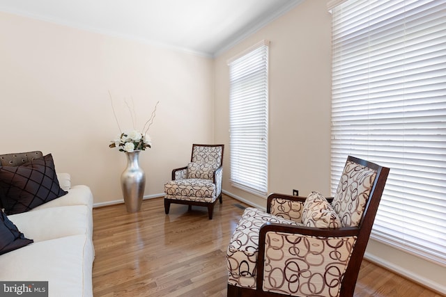 sitting room featuring light wood-style floors, crown molding, and plenty of natural light