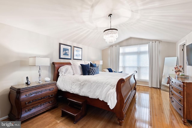 bedroom featuring a notable chandelier, vaulted ceiling, and light wood-type flooring