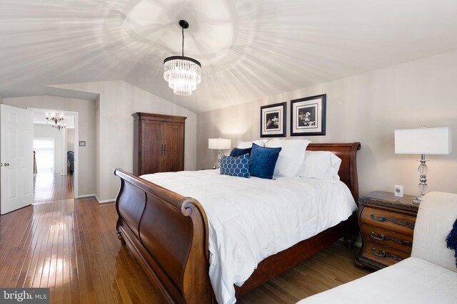 bedroom with an inviting chandelier, vaulted ceiling, and hardwood / wood-style flooring