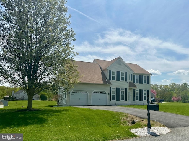 colonial house featuring a garage, driveway, and a front yard
