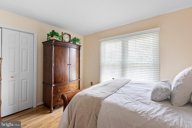bedroom with baseboards, a closet, and light wood finished floors