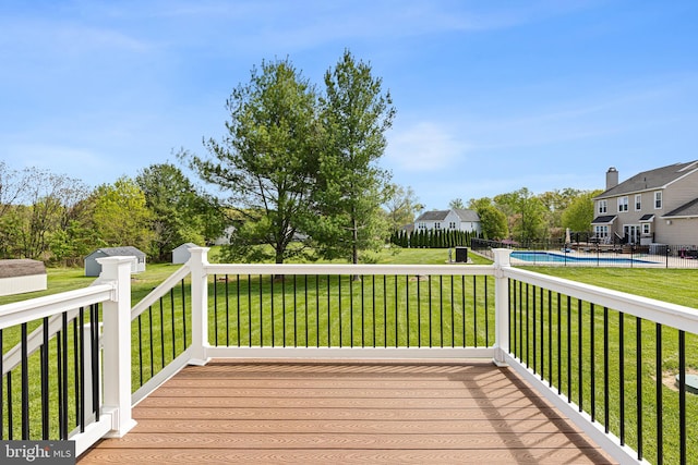 wooden terrace with fence, a fenced in pool, and a lawn