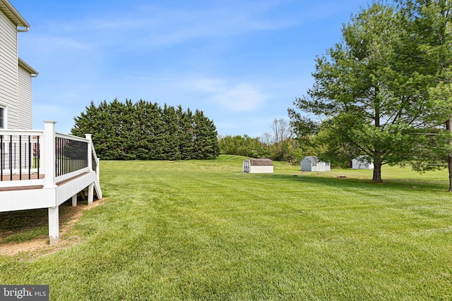 view of yard with an outdoor structure, a storage shed, and a deck