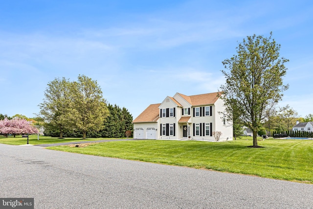 colonial inspired home with driveway, a front yard, and an attached garage