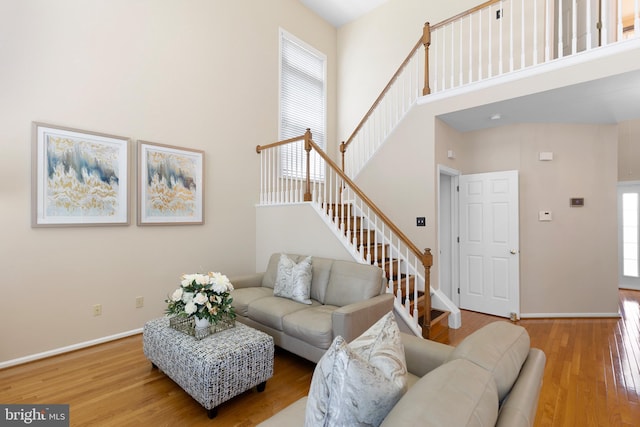 living room with wood finished floors, baseboards, stairs, and a high ceiling