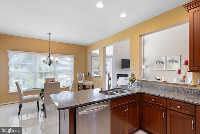 kitchen featuring dark stone countertops, a sink, dishwasher, decorative light fixtures, and a notable chandelier