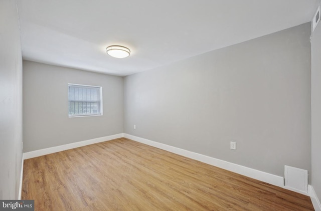 empty room featuring baseboards, wood finished floors, and visible vents