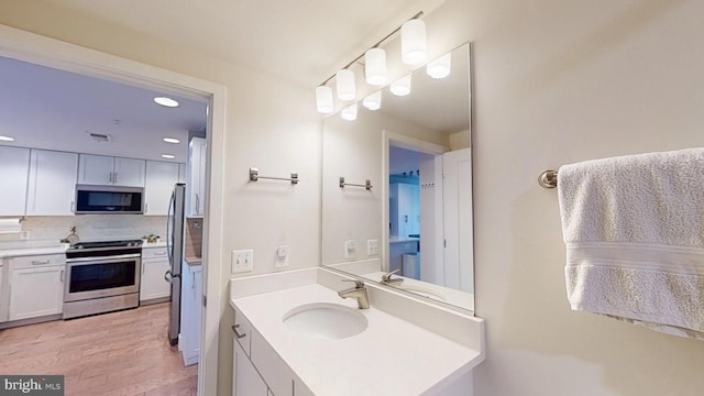 50 Florida Ave NE Unit 412, Washington, DC 20002 - bathroom with wood finished floors, vanity, backsplash, visible vents, and recessed lighting
