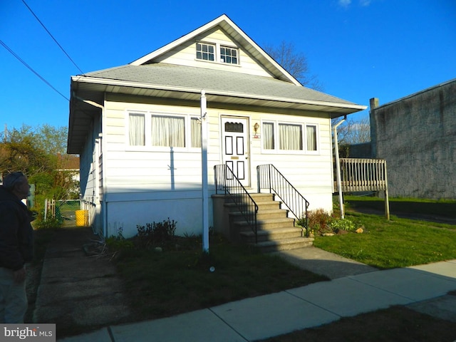 bungalow-style home with roof with shingles