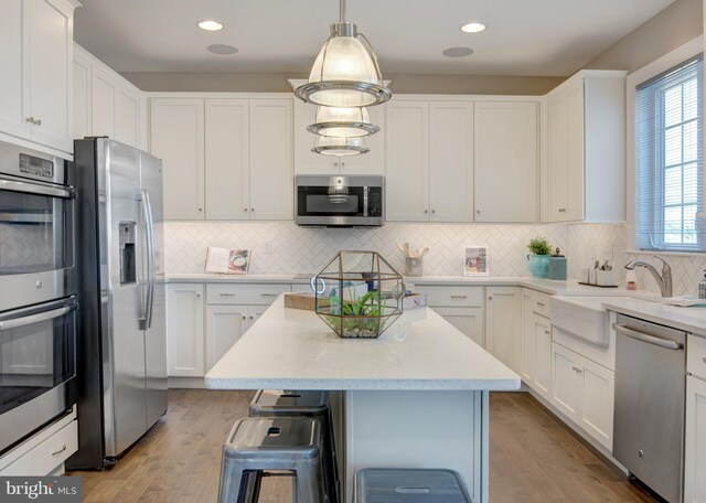 126 Green Forest Dr Unit 5Houston, Middletown, DE 19709 - kitchen featuring a kitchen island, white cabinetry, tasteful backsplash, a sink, and appliances with stainless steel finishes