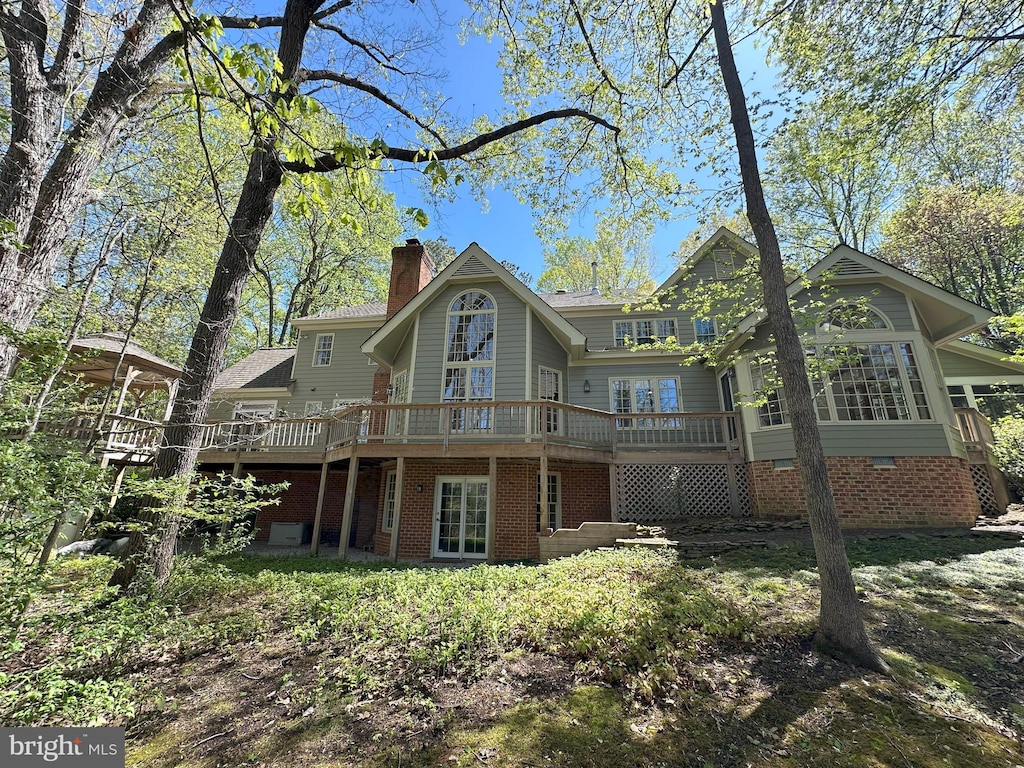 back of house with a wooden deck and a chimney