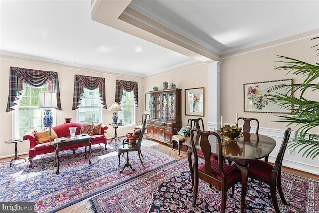 dining space with ornate columns, ornamental molding, a healthy amount of sunlight, and wood finished floors