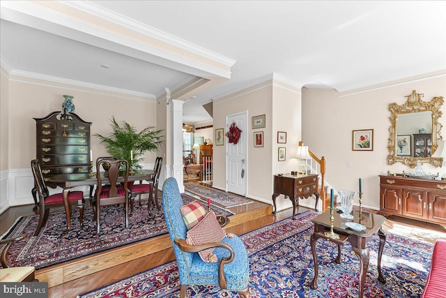 living room featuring ornate columns, wood finished floors, and ornamental molding