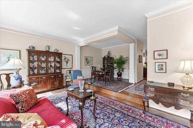 living area with decorative columns, ornamental molding, and wainscoting