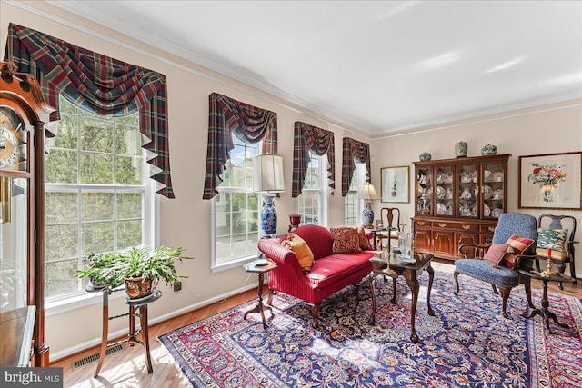 living area featuring crown molding, visible vents, wood finished floors, and baseboards