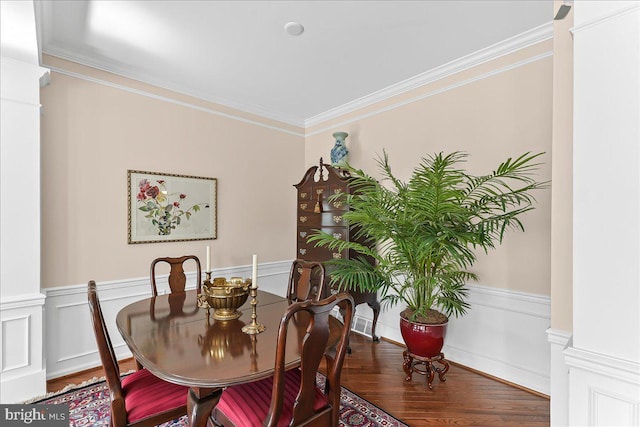 dining room featuring ornamental molding, a wainscoted wall, wood finished floors, and ornate columns