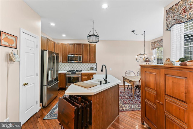kitchen featuring brown cabinetry, stainless steel appliances, dark wood-style flooring, and light countertops