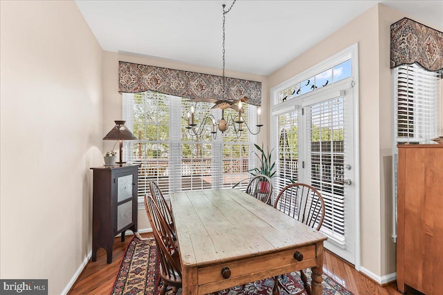 dining area with wood finished floors, a notable chandelier, and baseboards