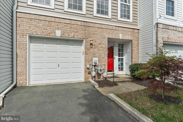 entrance to property with brick siding, driveway, and an attached garage