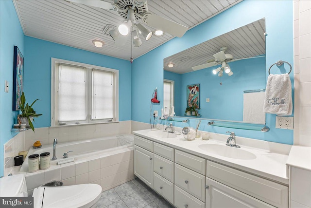 full bath featuring a sink, double vanity, ceiling fan, and tiled tub